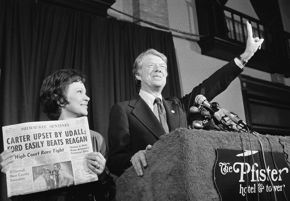 FILE - Jimmy Carter gives a victory sign as his wife, Rosalynn Carter, holds a newspaper after...