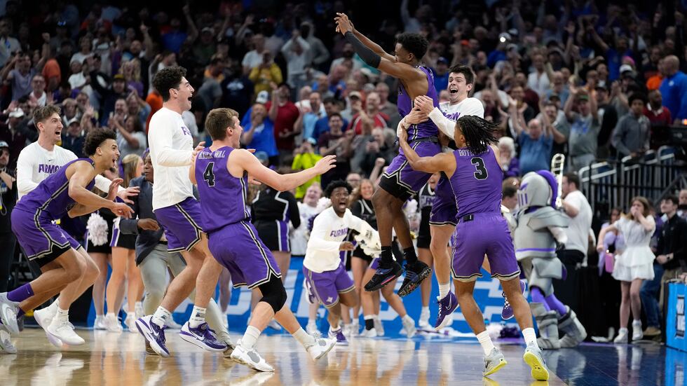 Furman guard JP Pegues, third from right, celebrates with the team after defeating Virginia in...