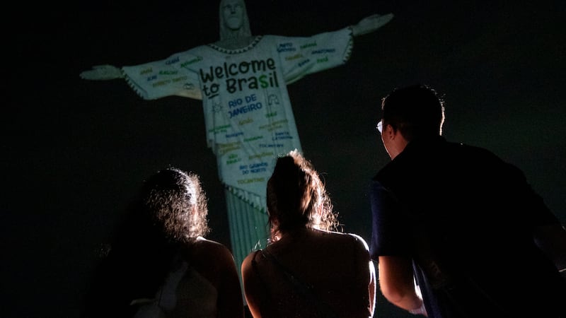 Fans look up at the Christ the Redeemer statue that is illuminated with a welcome message to...