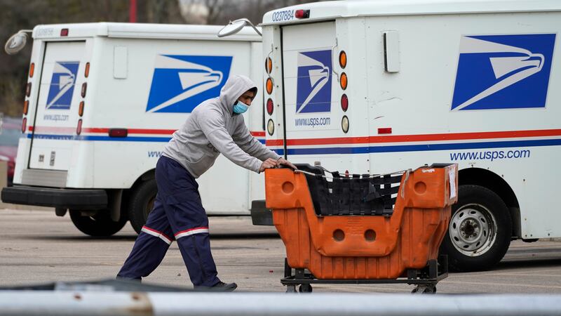 FILE - A United States Postal Service employee works outside a post office in Wheeling, Ill.,...